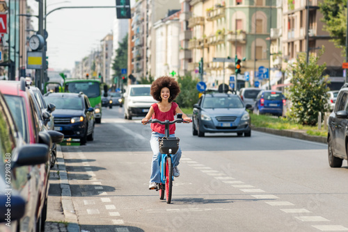 Positive black woman riding electric bicycle on city street