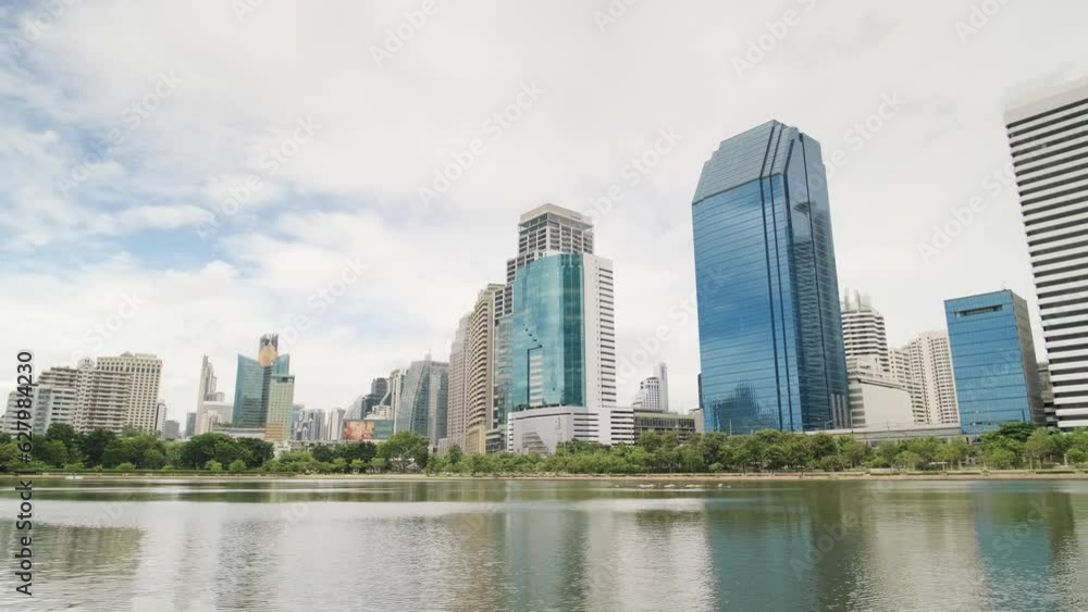 Benchakitti Park in Bangkok. Nearby, the skyscrapers of the business district are visible. A place of relaxation for residents, with a path around green areas. Skyscrapers, Urban park, Cityscape. Benchakitti Park in Bangkok. Nearby, the skyscrapers of the business district are visible. A place of relaxation for residents, with a path around green areas. Skyscrapers, Urban park, Cityscape.