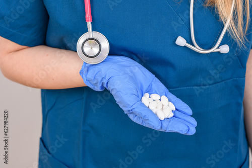 Pani doktor w kitlu trzyma garść lekarstw antybiotyków 