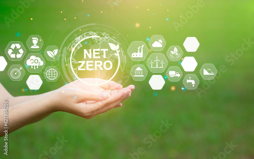 In the hand there is a carbon neutral NET ZERO icon. The concept of net zero carbon emissions and net greenhouse gas emissions. with many icons about the environment