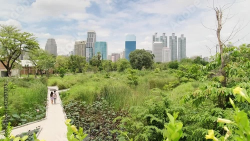 Benchakitti Park in Bangkok. Nearby, the skyscrapers of the business district are visible. A place of relaxation for residents, with a path around green areas. Skyscrapers, Urban park, Cityscape.
