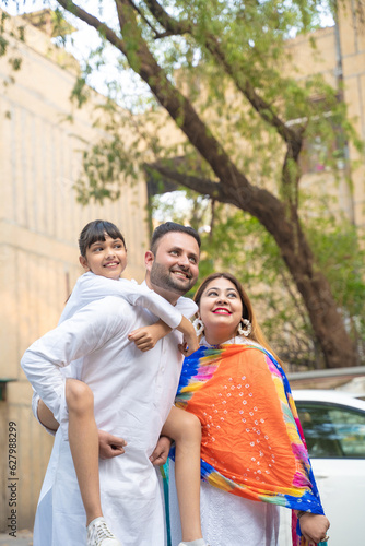 indian family standing outdoor and giving happy expression.