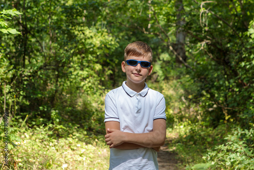 Portrait of a boy in sunglasses in nature, looking at the camera.