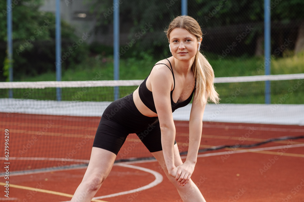 Caucasian sports woman doing warming exrcises outdoors on the sports ground