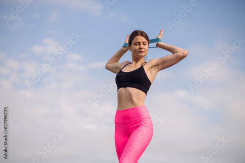 Caucasian sports woman doing exercises with a rubber outdoors the lawn playground