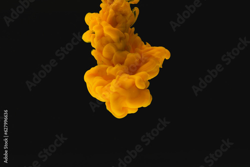 Close up of bright orange ink in water with copy space on black background