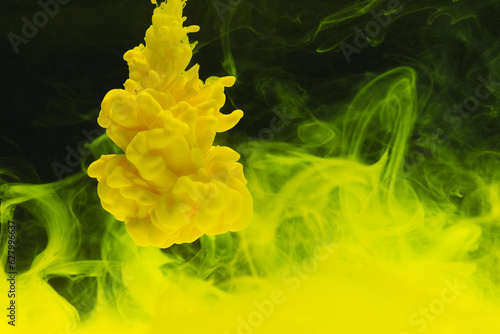 Close up of bright yellow ink in water with copy space on black background