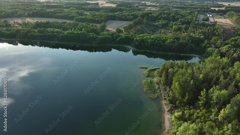 Aeria view of Osadnik Gajówka artificial lake (waste pond) in Gmina Przykona, within Turek County, Greater Poland Voivodeship, Poland. Green forest landscape and sunshine Aeria view of Osadnik Gajówka artificial lake (waste pond) in Gmina Przykona, within Turek County, Greater Poland Voivodeship, Poland. Green forest landscape and sunshine
