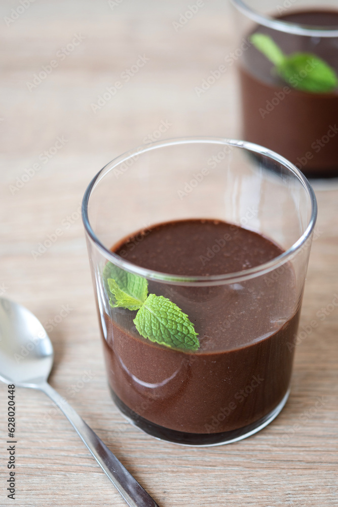 Chocolate mousse dessert garnished with mint leaf on wooden table Chocolate mousse dessert garnished with mint leaf on wooden table
