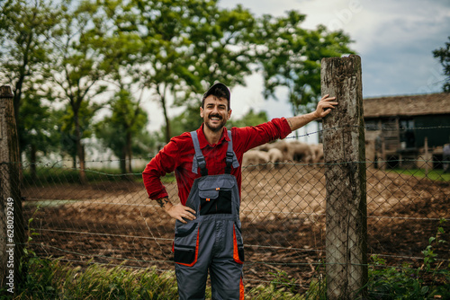 Portrait of a proud male farmer in a working suit standing in front of his farm.