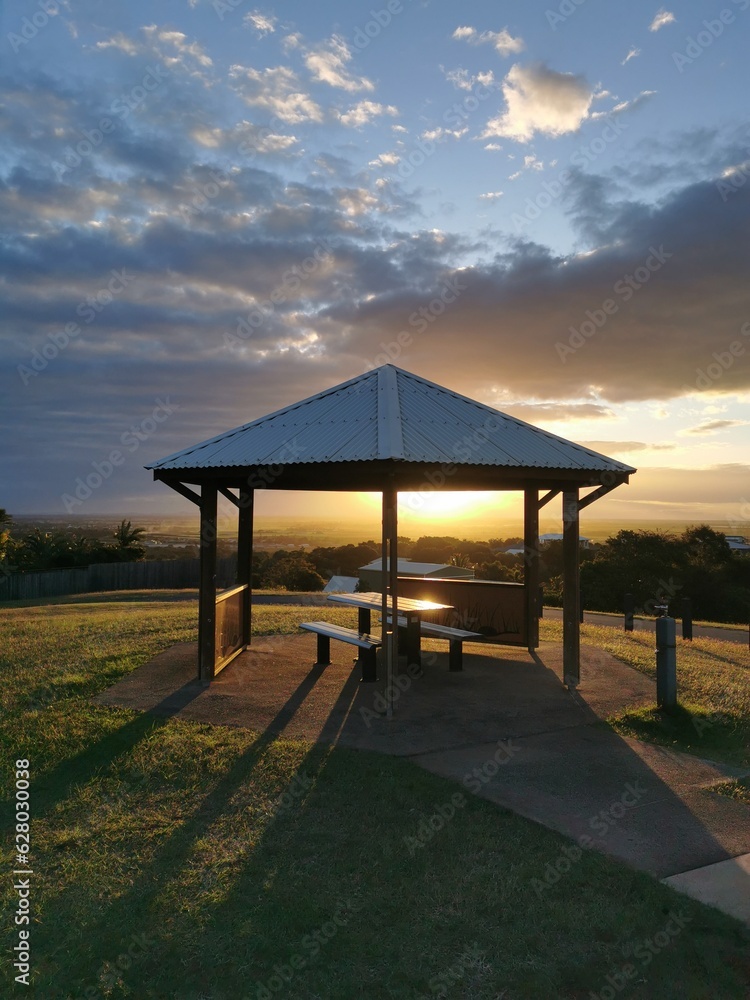 A pavilion in the sunset light, sky and clouds. The light goes through the building making long shadows. A pavilion in the sunset light, sky and clouds. The light goes through the building making long shadows.
