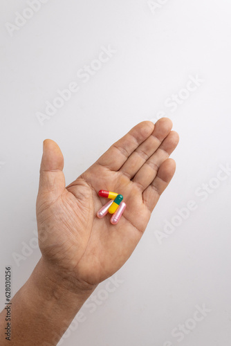 Four pill capsules in the hand.