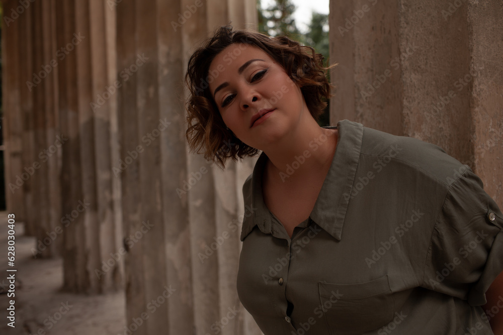 Portraiy of a beautiful girl is wearing a khaki t-shirt, the overweight woman posing against stone biege wall. The fashion outfit for plus-size woman for the city, minimalizm urban style clothes Portraiy of a beautiful girl is wearing a khaki t-shirt, the overweight woman posing against stone biege wall. The fashion outfit for plus-size woman for the city, minimalizm urban style clothes