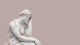 Marble statue of Aphrodite in a thinks pose on a pastel background