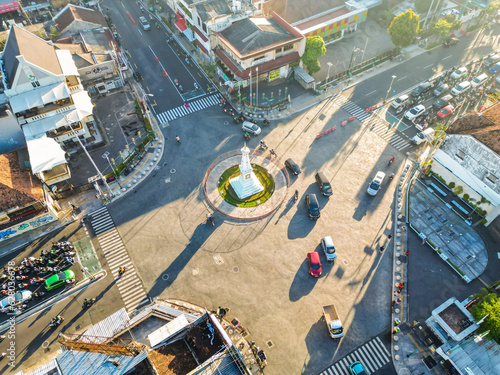 Aerial view of Tugu Jogja or Tugu Pal with crowded vehicles traffic in the morning sunlight. Jogjakarta famous iconic building as tourist destination. White monument of Yogya. Tugu Golog Gilig.