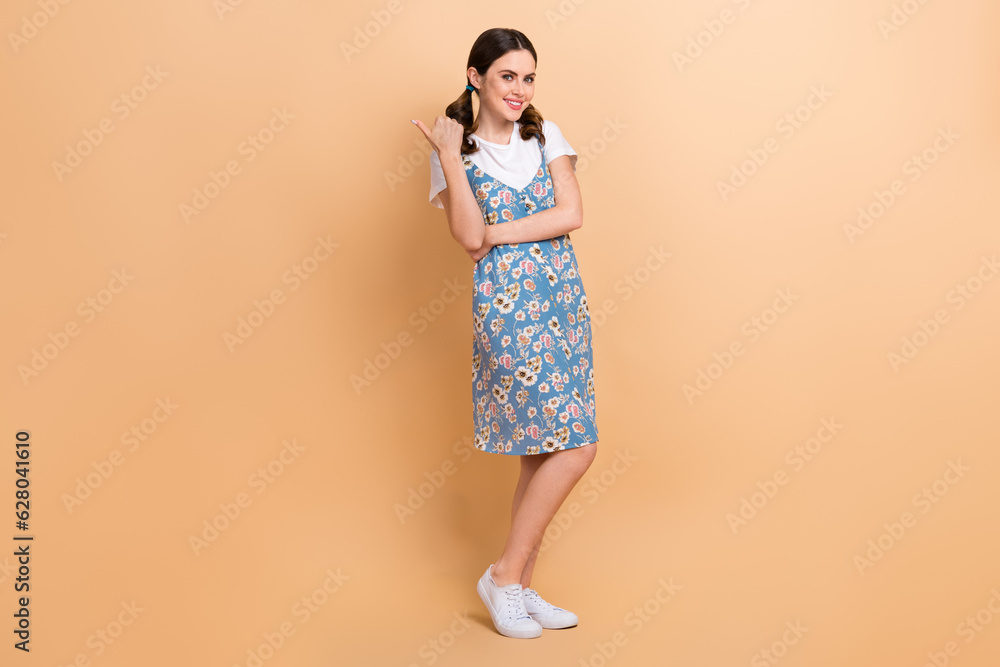 Full body photo of young positive girl summertime style outfit dress direct finger empty space travel agency isolated on beige background Full body photo of young positive girl summertime style outfit dress direct finger empty space travel agency isolated on beige background