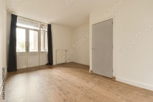 an empty room with wooden floors and white walls  there is a door leading to the left side of the room