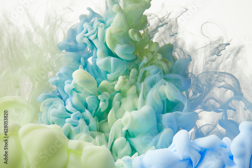 Splash of blue and green paints in water over white background