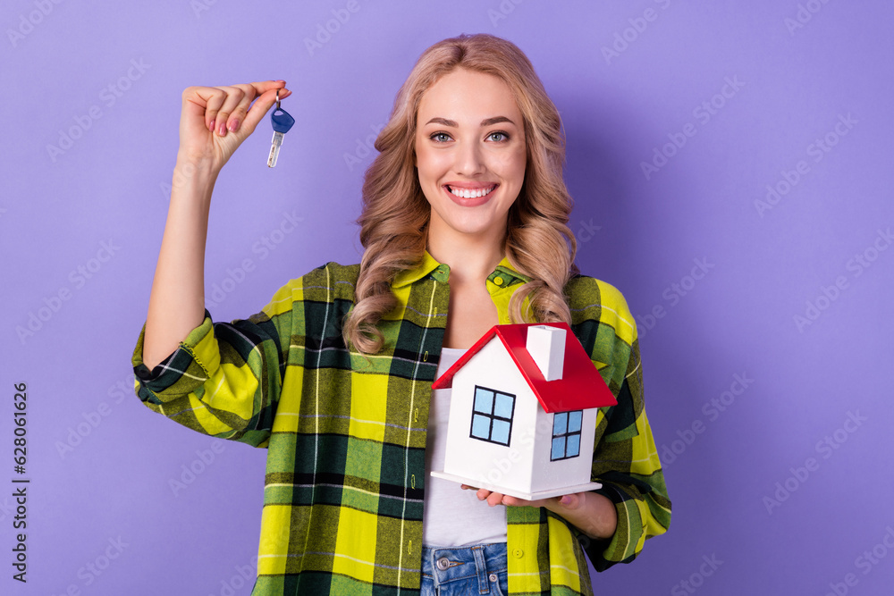 Portrait of cute cheerful girl toothy smile arms hold demonstrate house key isolated on purple color background Portrait of cute cheerful girl toothy smile arms hold demonstrate house key isolated on purple color background