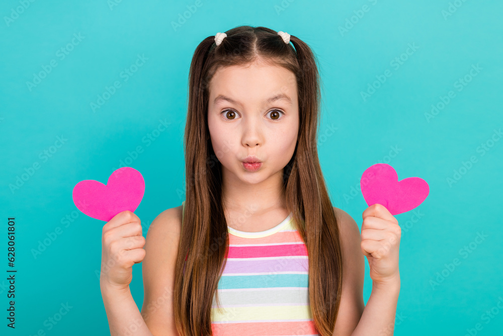 Photo of charming cute playful girl wear stylish striped clothes two hands hold pink heart shape send kiss isolated blue color background Photo of charming cute playful girl wear stylish striped clothes two hands hold pink heart shape send kiss isolated blue color background