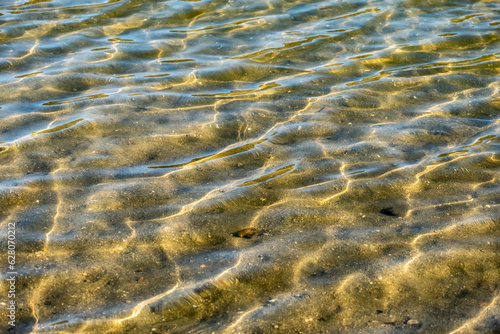 Gentle and relaxing waves of clear water on the shore of a lake.