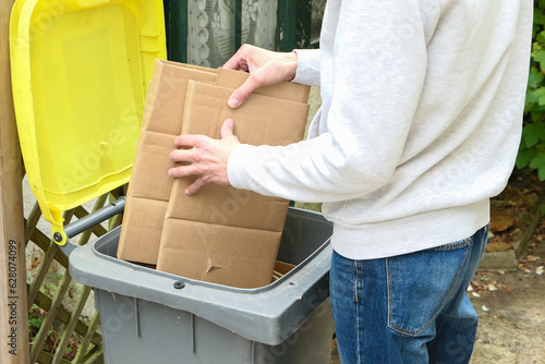 A person who sorts packaging waste. Man putting packing boxes into yellow bin for recycling
