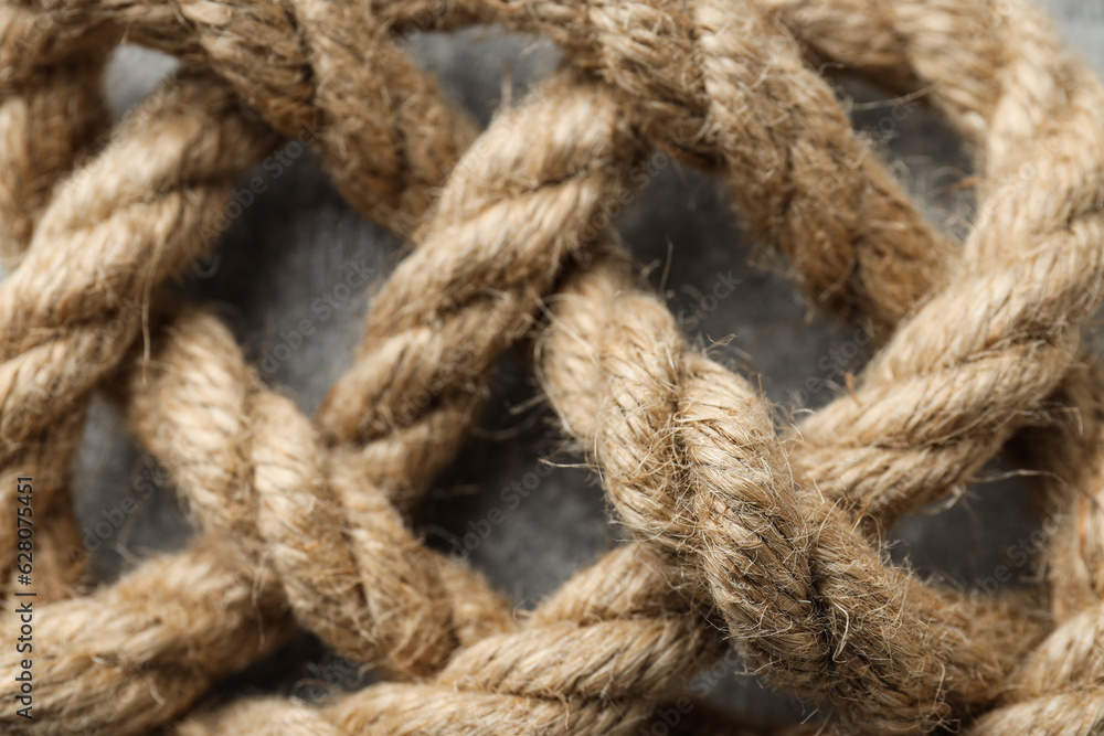 Thick knotted rope close-up on gray background Thick knotted rope close-up on gray background
