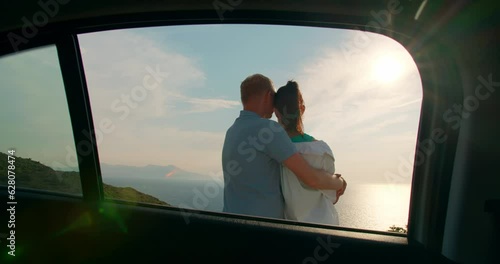 Heterosexual romantic couple hugging next to car during sunset, travel dream in honeymoon  photo