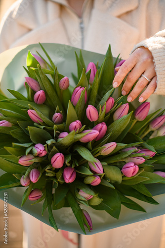 Selective focus on spring bouquet of pink tulips in woman's hands