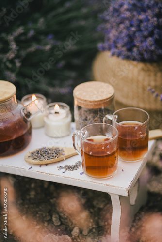 Natural herbal lavender tea on a white wooden tray in a middle of beautiful purple lavender field.