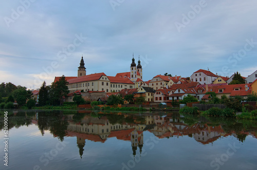 Scenic morning cityscape of medieval town of Telc in the Czech Republic. The castle and colorful buildings reflected in calm water in the lake. Travel and tourism concept. UNESCO World Heritage Site