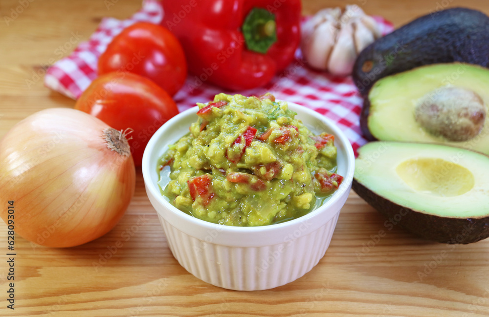 Bowl of Homemade Guacamole with Fresh Avocadoes, Onions and Tomatoes Around