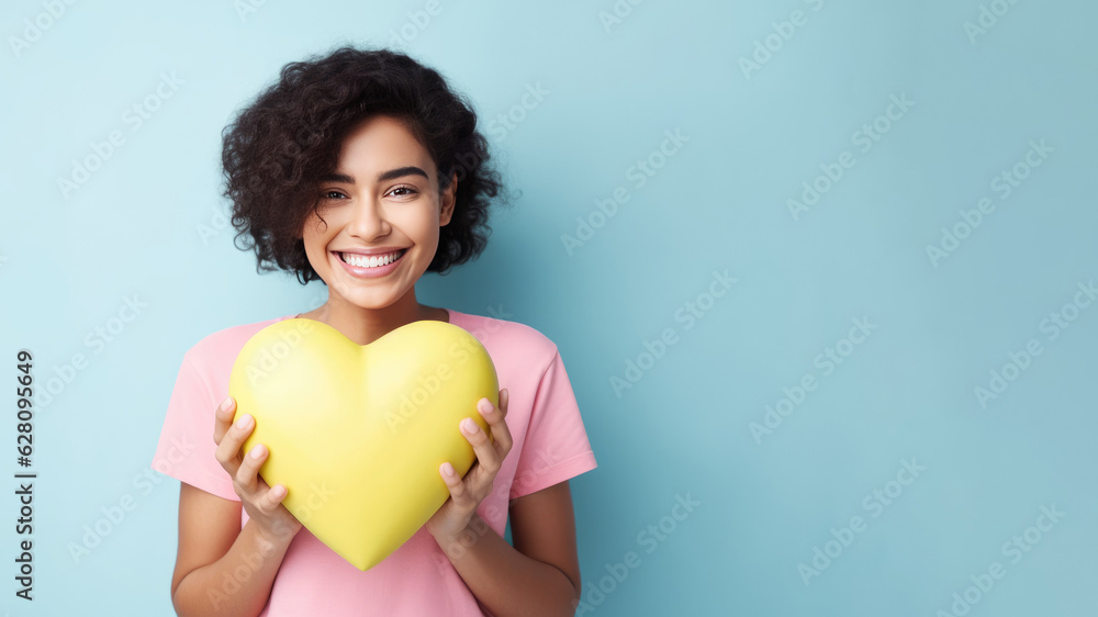 Smiling woman holding small plastic heart isolated on blue background. AI Generated.