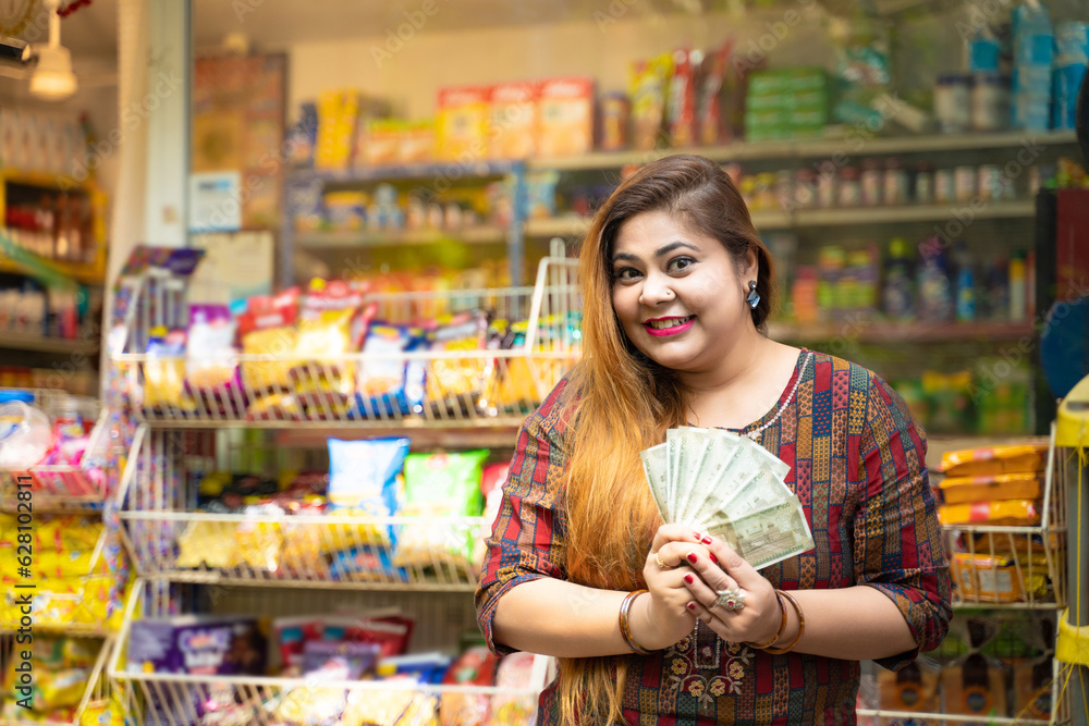 Indian woman showing money at grocery shop.