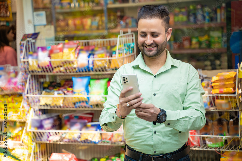 Indian man using smartphone at grocery shop.