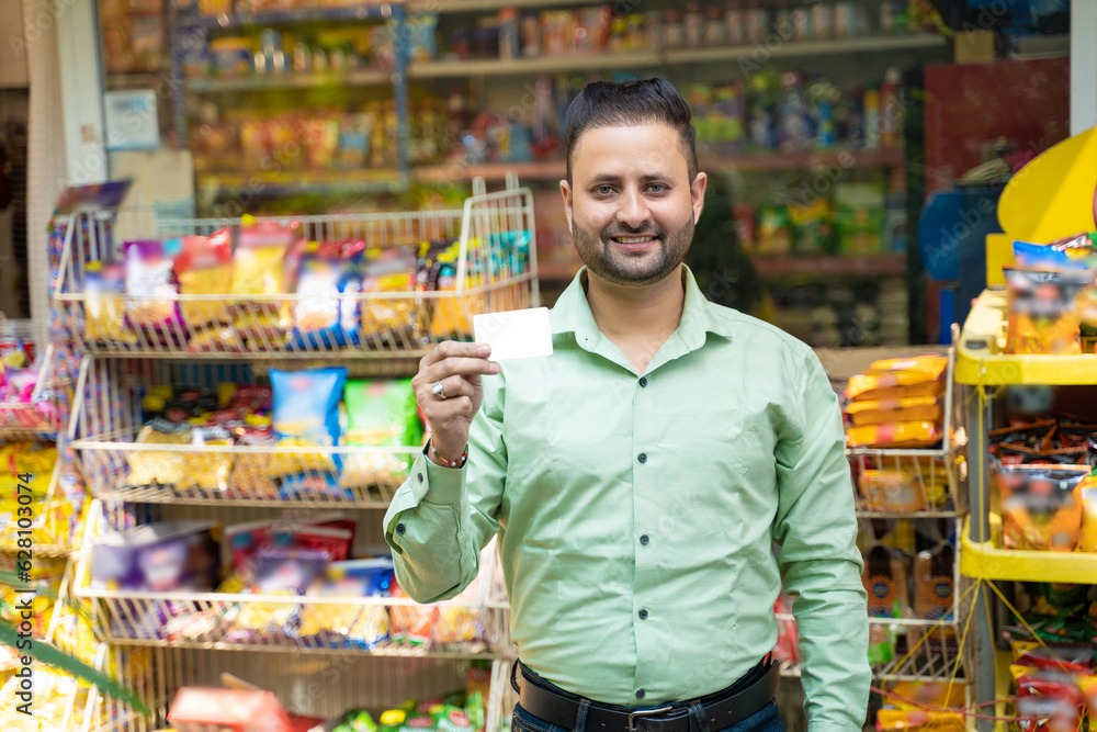 Indian man showing bank card at grocery shop.