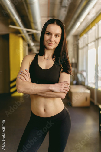 Sporty young woman in fashion sporty outfit standing alone in a gym after a workout session