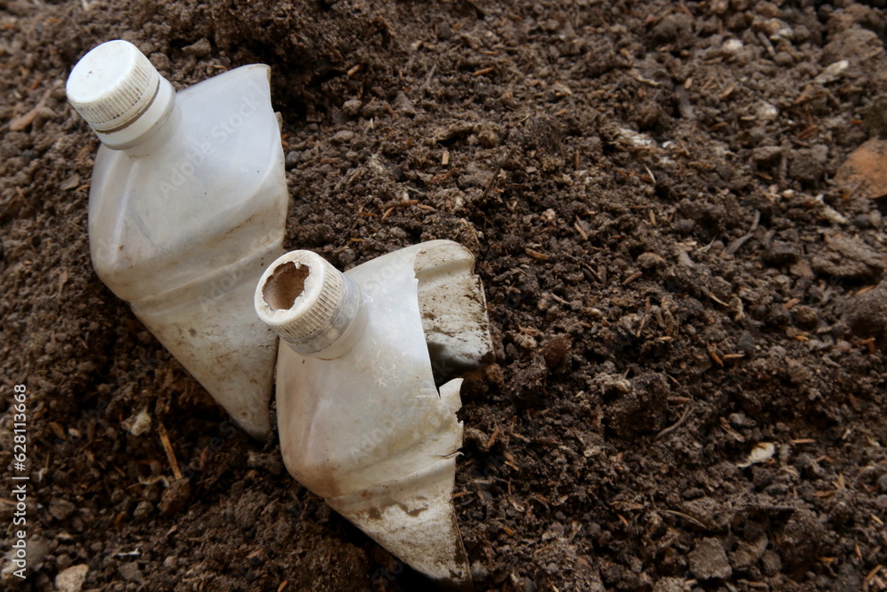 Obraz premium White cut half plastic bottle on dark brown color organic fertilizer.
