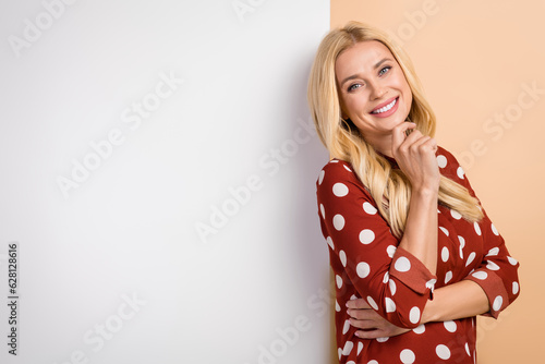 Photo of minded pretty lady hand touch chin empty space advert billboard isolated on beige color background © deagreez