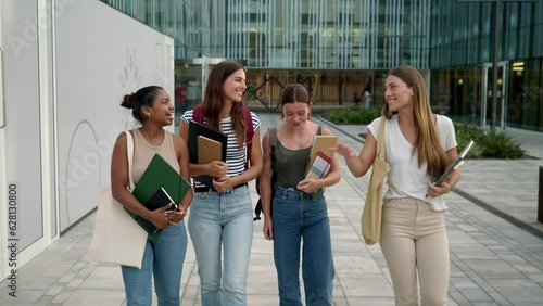 Group of diverse teenage student girls walking and chatting on campus