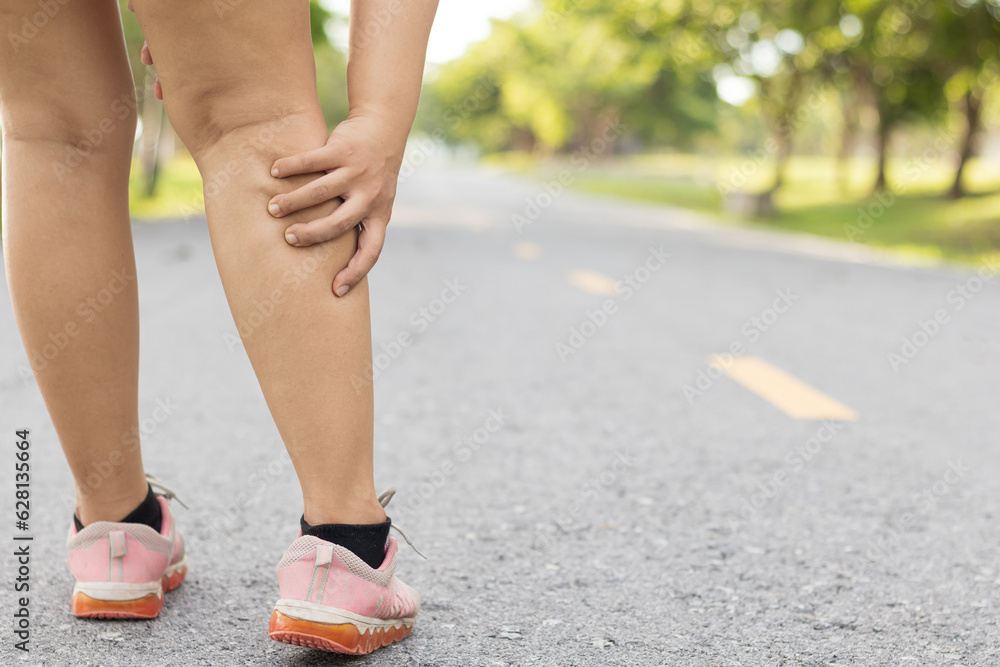 Injury from workout concept. Running sport injury leg pain. Runner woman massaging sore calf muscles during running training outdoor from pain. Female athlete with joint or muscle soreness. Injury from workout concept. Running sport injury leg pain. Runner woman massaging sore calf muscles during running training outdoor from pain. Female athlete with joint or muscle soreness.