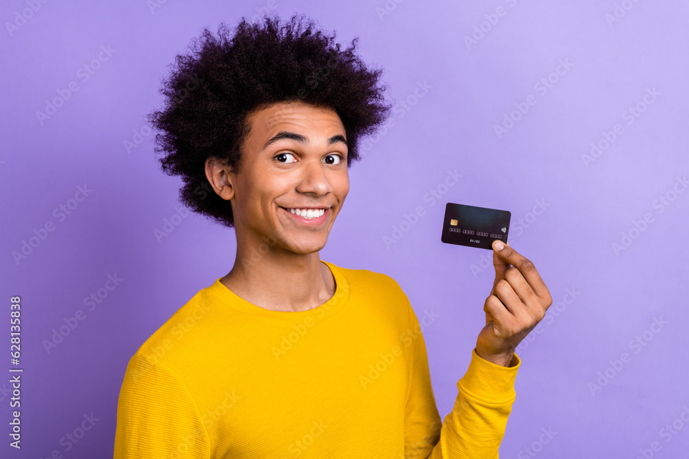 Photo portrait of young promoter advertiser man hold debit plastic card payment online with no taxes isolated on purple color background Photo portrait of young promoter advertiser man hold debit plastic card payment online with no taxes isolated on purple color background