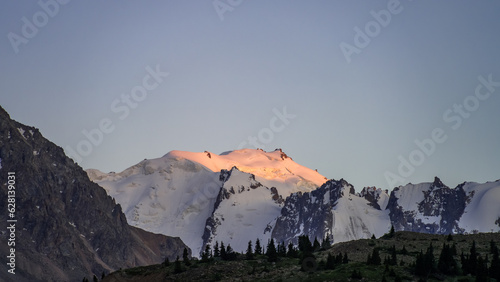 snowy mountain peaks. the green plateau of the foothills. summer mountains