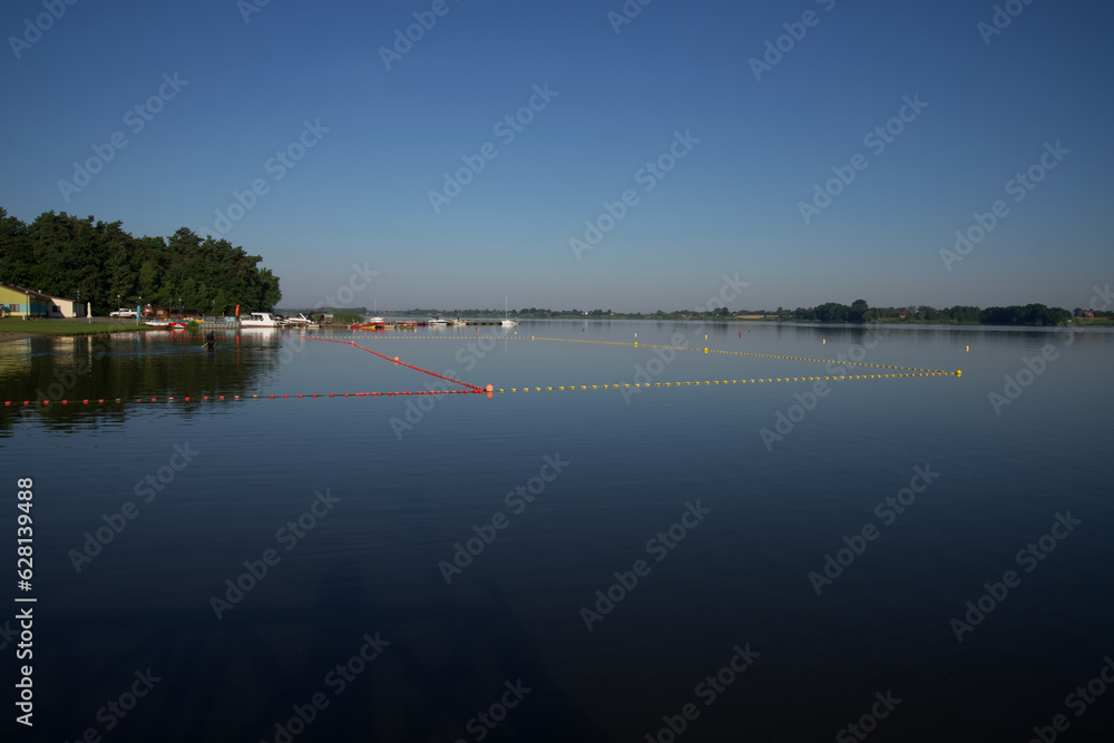 Plaża i kąpielisko, zbiornik wodny z możliwością kompania, lato nad wodą błękitne bezchmurne niebo na dole woda.