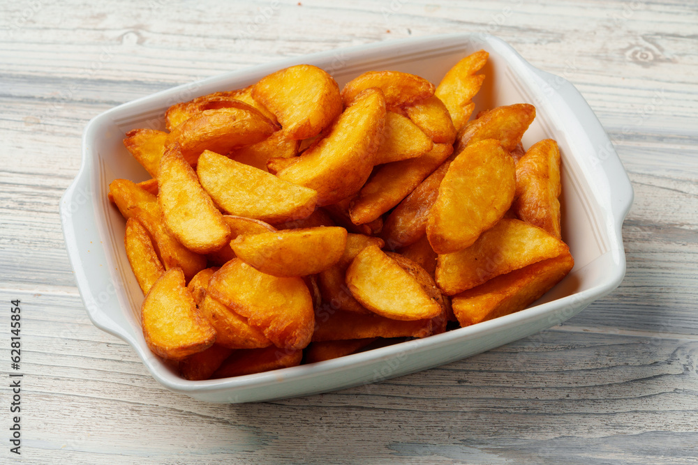 Fried potato wedges in white ceramic bowl Fried potato wedges in white ceramic bowl