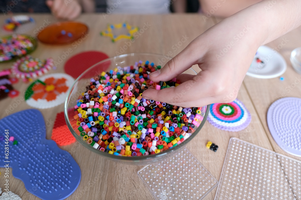 closeup of children's hands creating perler bead patterns, make crafts