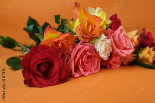 bouquet of yellow  red  pink roses with a copy space for the designer  flowers for professional holiday on an orange background  concept of mother s  Valentine s day  birthday  selective focus