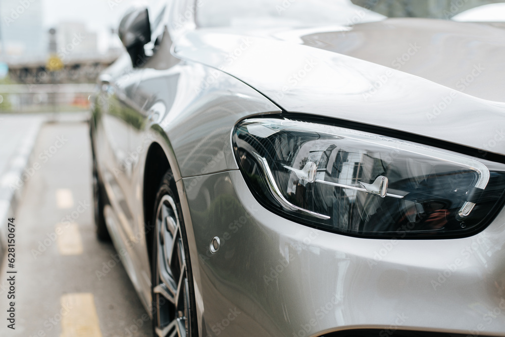 Fototapeta premium Close-up of stylish gray car luxury front headlight design outdoors.
