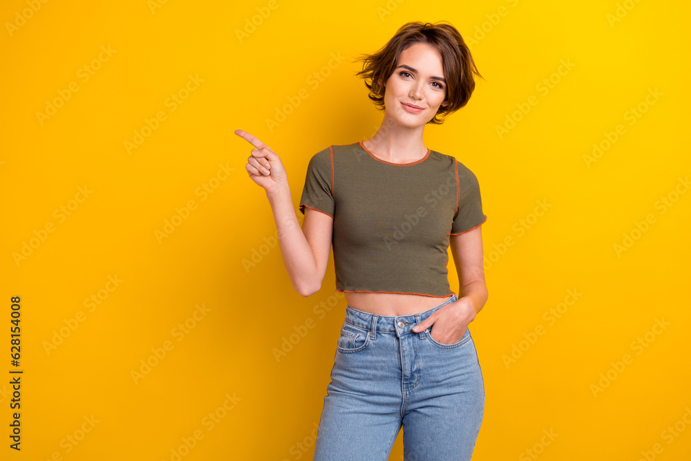 Portrait of gorgeous girl with short hairdo wear khaki t-shirt arm in pocket directing empty space isolated on yellow color background Portrait of gorgeous girl with short hairdo wear khaki t-shirt arm in pocket directing empty space isolated on yellow color background