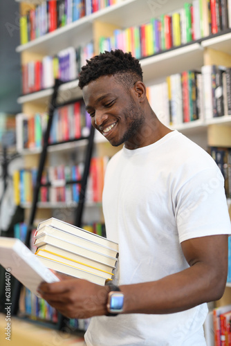 A black man with a smile buys books in a store.